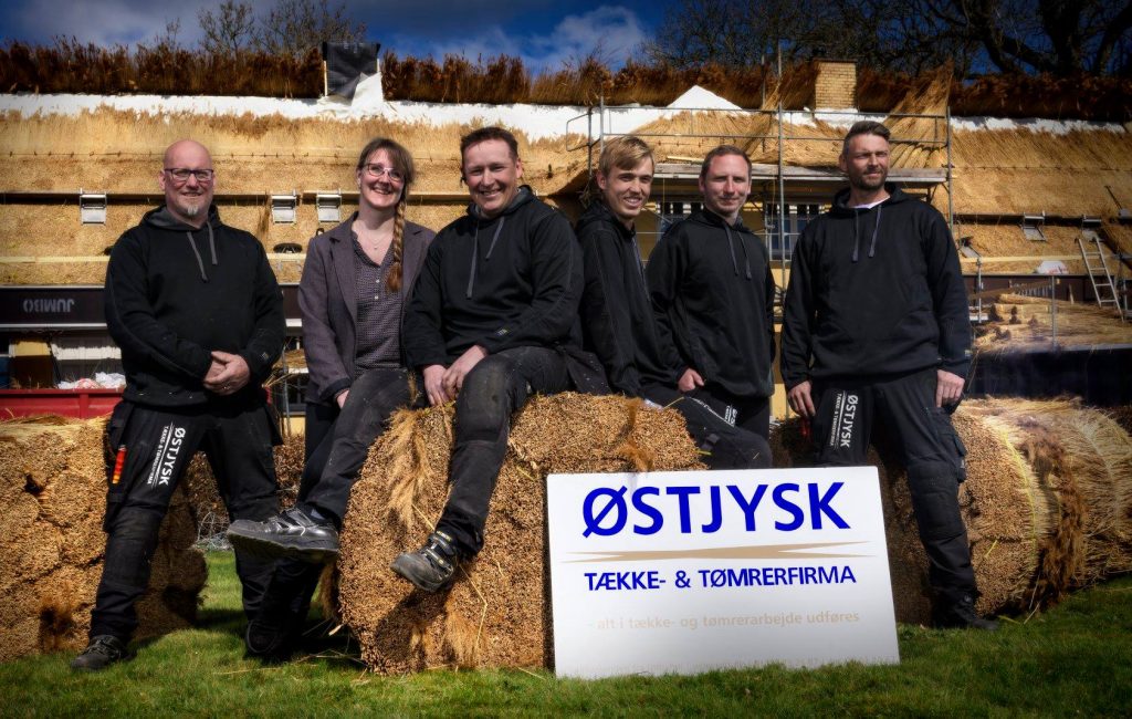 Tækkemand Jan Plauborg omgivet af hele Østjysk Tække- og tømrerfirma teamet